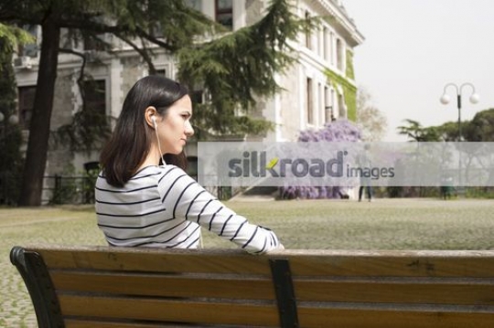 Woman on the bench listening to music|