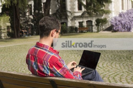 Student sitting on the bench using the laptop |