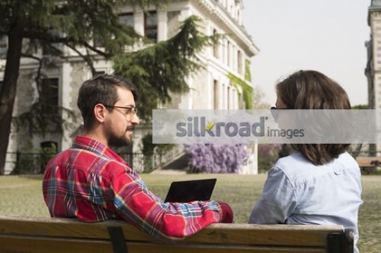 University Students sitting on the bench together studying|