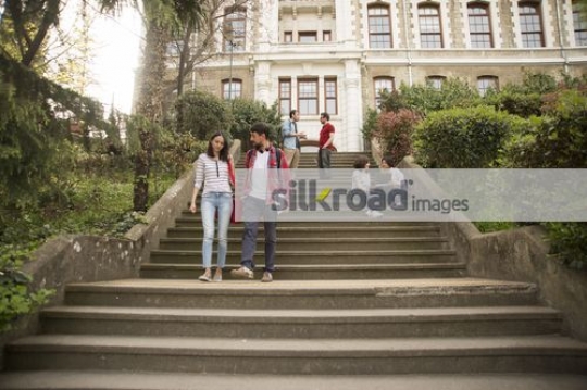 Two University students going down the stairs together|
