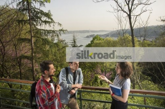 Two men standing talking to the woman|
