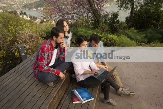 Group of students sitting together using the laptop|