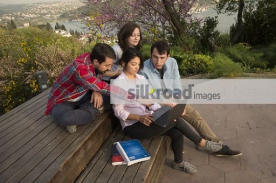 University Students sitting on the bench using the laptop|