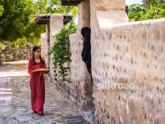 Little girl walking with plate toward neighbor|-