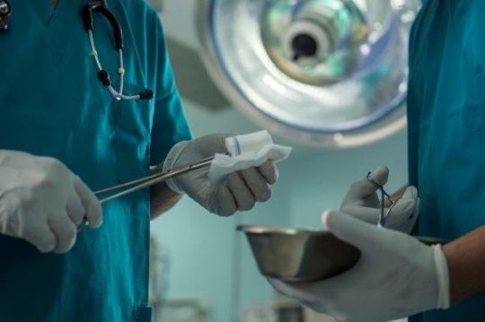 A Surgeon Holding Scissors and Cotton