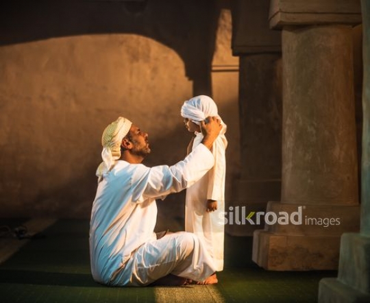 Old man fixing boy's headdress|-