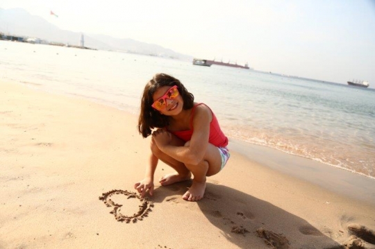 Little Girl Drawing A Heart In Sand