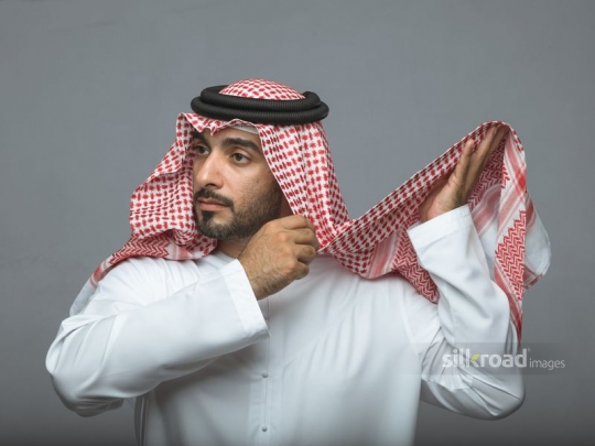 Middle Eastern man fixing his traditional attire