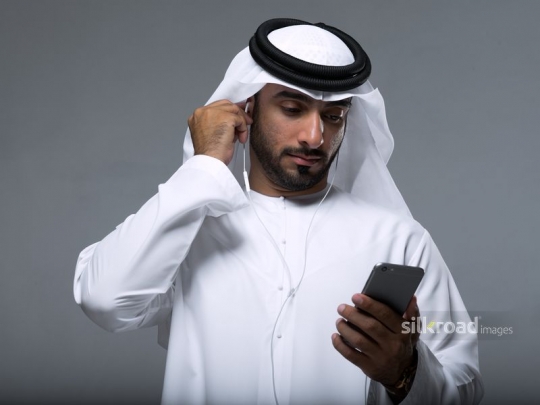 Arabian man fixing his earphones