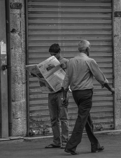 young man reading the newspaper in street