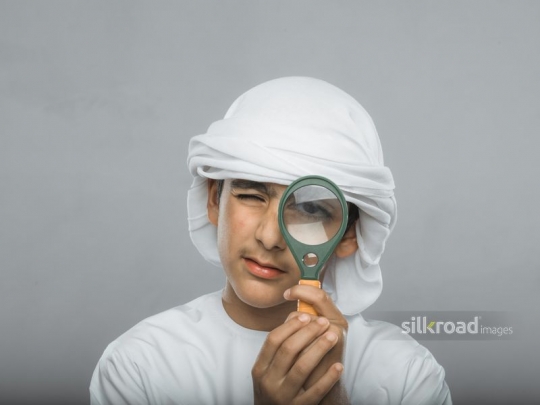 Arabian boy looking through magnifier glass