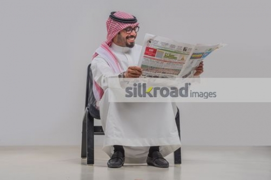 Middle Eastern man sitting and reading the newspaper