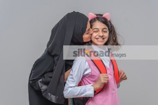 Middle Eastern woman kissing the young girls cheek|