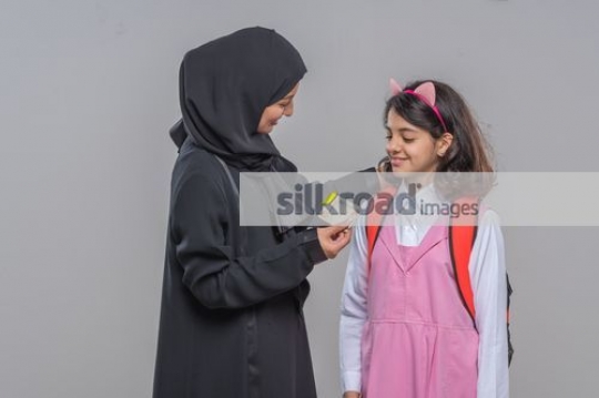 Middle Eastern woman giving money to the young kid