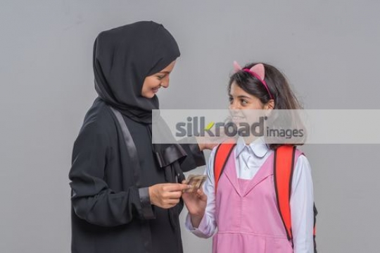 Arab woman giving the young kid money|