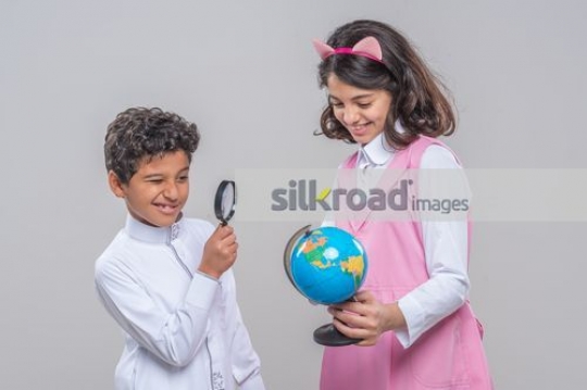 Young Arab kids looking at the mini globe|