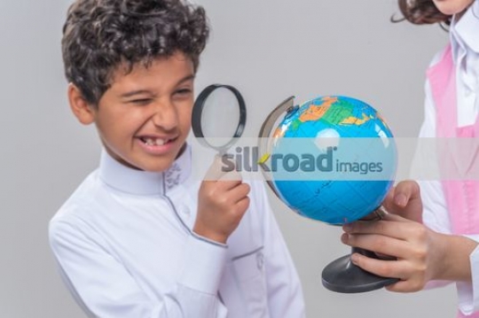 Middle Eastern kid looking at the mini globe