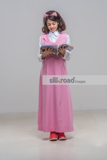 Arab kid standing reading the book