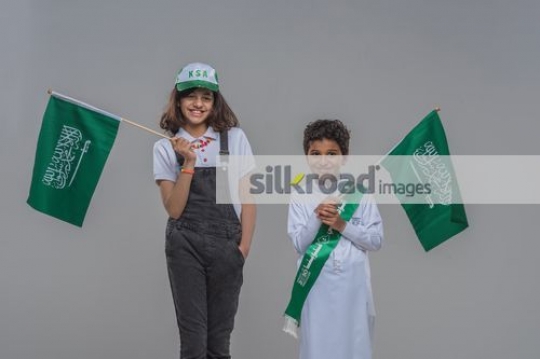 Arab kids standing each carrying a flag