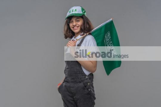 Young Middle Eastern girl carrying the KSA flag|