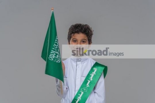 Arab boy carrying a Saudi Flag