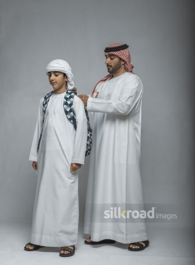 Father helping his son carry the school bag