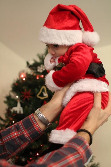 Newborn baby with Santa Hat, held by his father