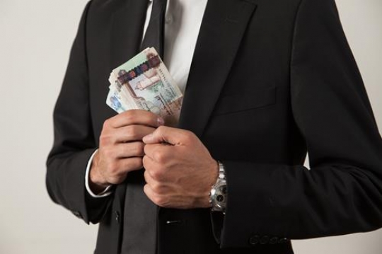 businessman putting money in his jacket pocket