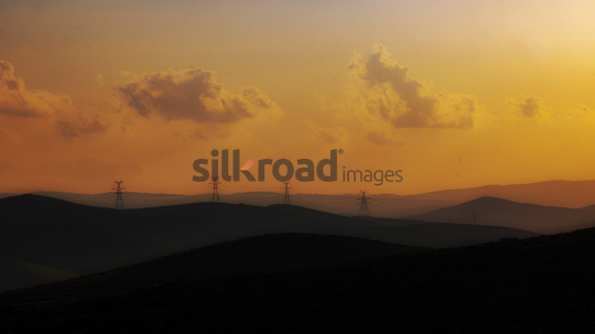 Golden Sunset Landscape with Electric Towers and Rolling Hills