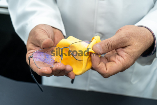 Hands Cleaning Eyeglasses with Cleaning Spray