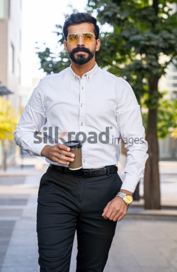Man Walking Between Modern Buildings with Coffee Cup in Al Abdali Boulevard