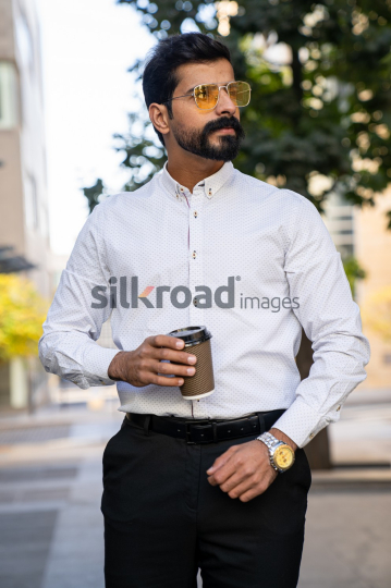 Man Walking Between Modern Buildings with Coffee Cup in Al Abdali Boulevard