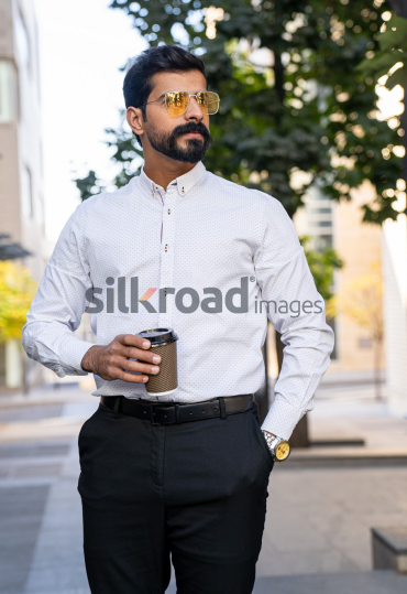 Man Walking Between Modern Buildings with Coffee Cup in Al Abdali Boulevard