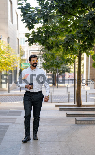 Man Walking Between Modern Buildings with Coffee Cup in Al Abdali Boulevard
