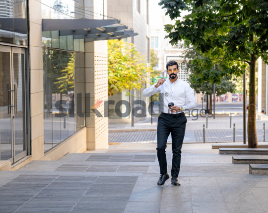Man Walking Between Modern Buildings with Coffee Cup in Al Abdali Boulevard