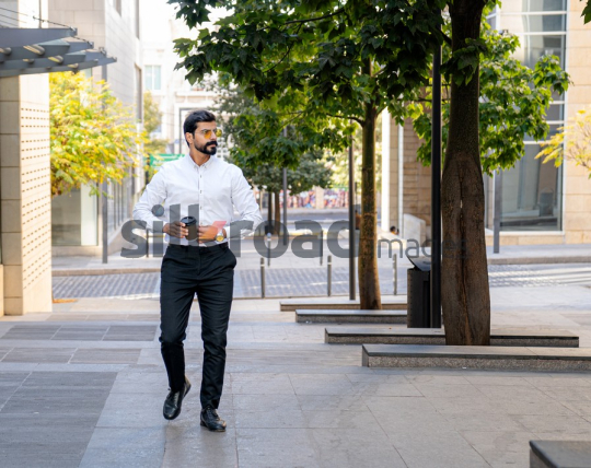 Man Walking Between Modern Buildings with Coffee Cup in Al Abdali Boulevard