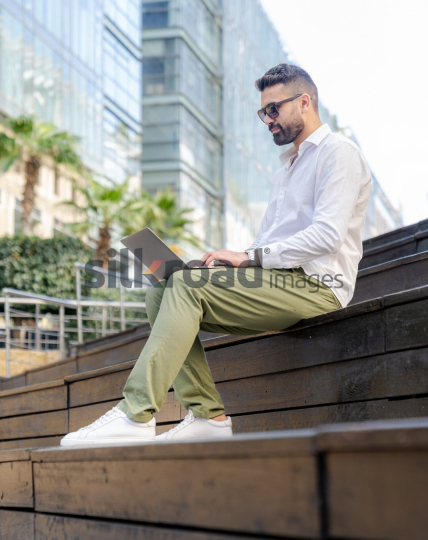 Man Working on Laptop Outdoors at Sunrise in Jordan's Al Abdali Boulevard