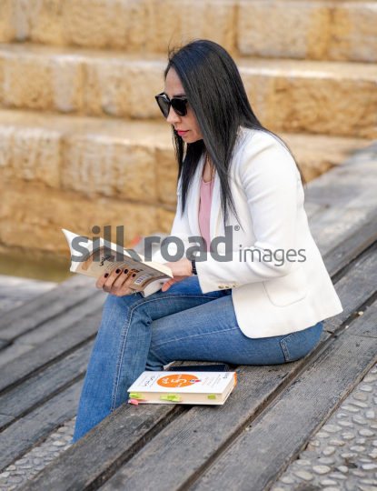 Professional Arab Woman Reading and Working Outdoors in Jordan's Al Abdali Boulevard