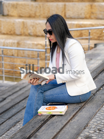 Professional Arab Woman Reading and Working Outdoors in Jordan's Al Abdali Boulevard