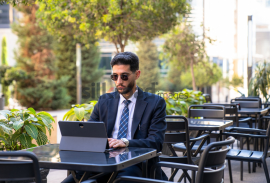 Professional Man in Suit with Sunglasses Working on Laptop in Open Area on Amman Boulevard, Jordan