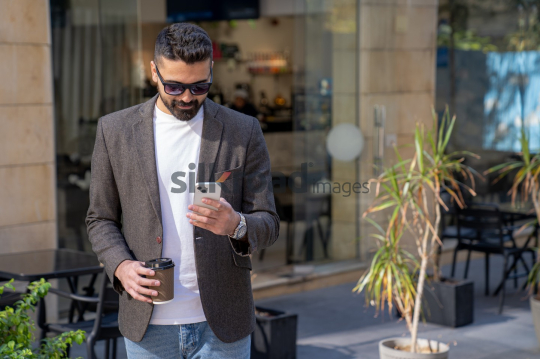 Professional Man Leaving Coffee Shop with Coffee and Phone in Sunlight