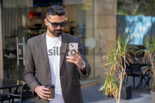 Professional Man Leaving Coffee Shop with Coffee and Phone in Sunlight
