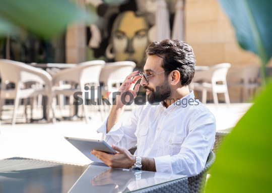 Professional Man Sitting at Desk with Sunglasses, Smiling and Looking to the Side