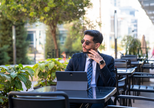 professional man, suit, sunglasses, laptop, desk work, Amman Boulevard, Jordan, outdoor workspace, thinking, showcase, deep thought, bustling restaurant, urban environment, productivity, business, wor