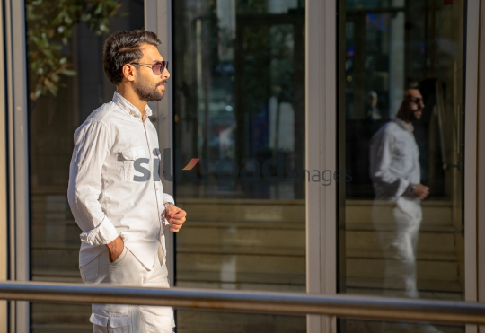Professional Man Walking Past Glass Door in Morning Light at Al Abdali Boulevard