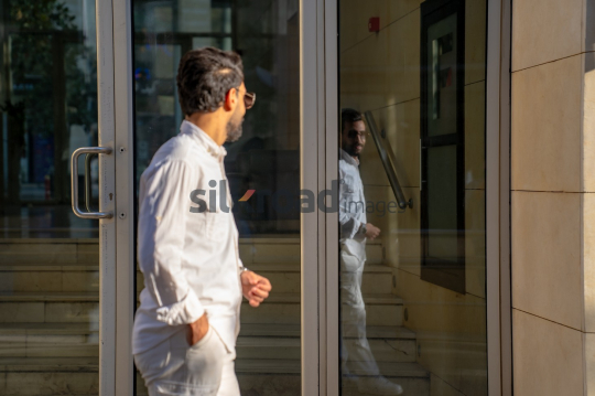 Professional Man Walking Past Glass Door in Morning Light at Al Abdali Boulevard