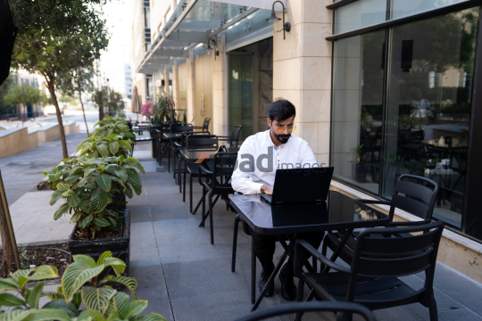 Professional Man Working on Laptop at Desk in Open Area on Amman Boulevard, Jordan