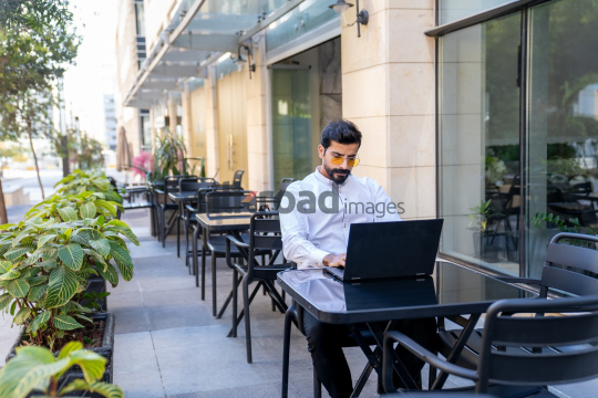 Professional Man Working on Laptop at Desk in Open Area on Amman Boulevard, Jordan