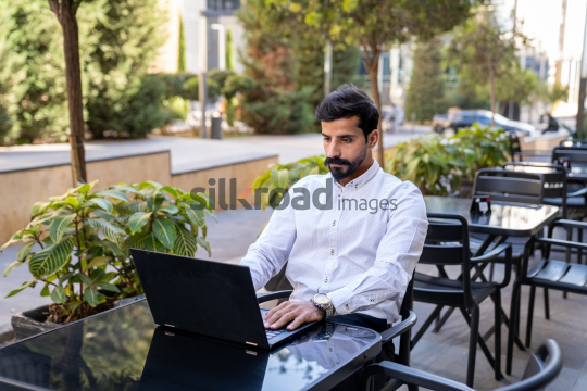 Professional Man Working on Laptop at Desk in Open Area on Amman Boulevard, Jordan