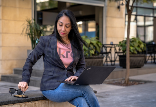 Professional Woman Working on Laptop in Al Abdali Boulevard with Sunglasses